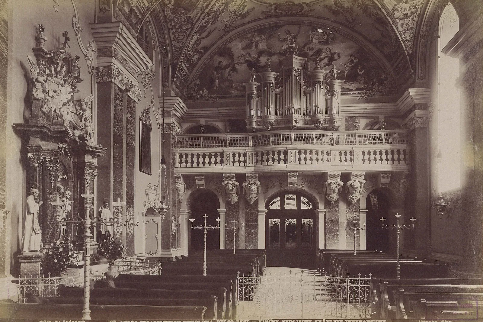 A sepia photograph of the church interior from around 1892, showing the organ gallery above a balustrade, marble pilasters, an altar on the left and rows of pews in front