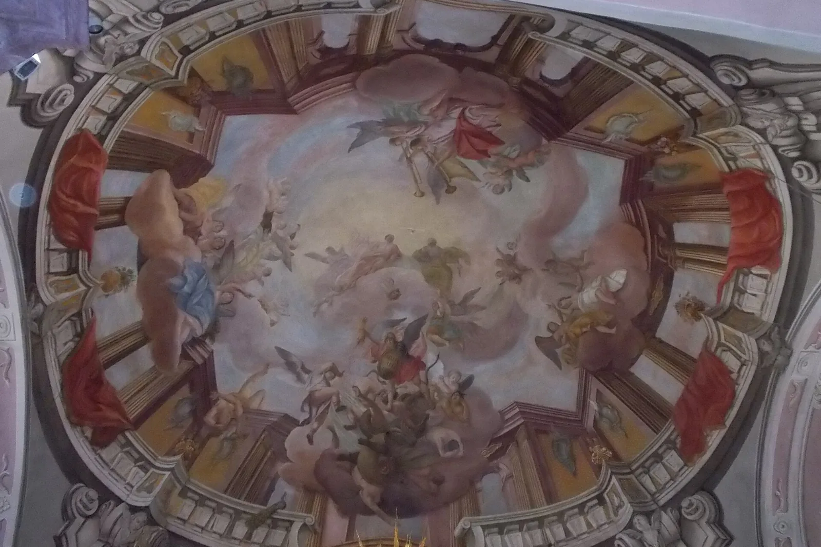 A ceiling fresco in the church, an oval scene of figures among clouds framed by painted architecture and plasterwork